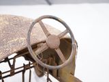 an old rusty car with a steering wheel sitting on the ground