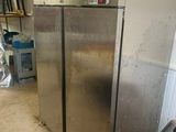 a silver refrigerator in the middle of a dirty room