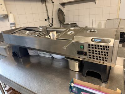 plan de travail en acier inoxydable dans une cuisine professionnelle équipée de nombreux appareils électroménagers