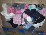 a cardboard box filled with clothes and clothes on the floor