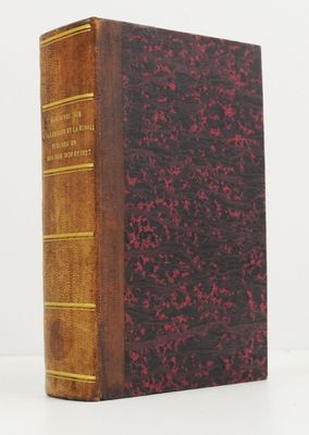 an old book with a red cover sitting on top of a white table