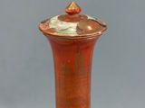 a red vase with a gold lid on a table