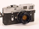 a black and silver camera sitting on a white surface