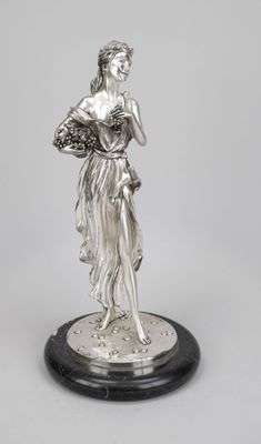 une statue en argent représentant une femme tenant un panier de fleurs