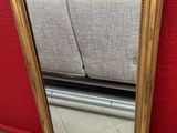 gold framed mirror on the floor in front of a red wall