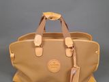 a tan leather handbag with two handles on a grey background