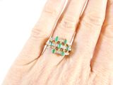 an image of a woman ' s hand with a diamond and emerald ring
