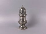an antique silver salt shaker sitting on top of a white surface