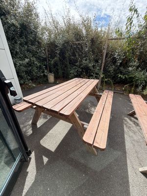une table de pique-nique en bois avec deux bancs dans le jardin derrière la maison