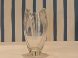 a glass vase sitting on a table in front of a striped wall