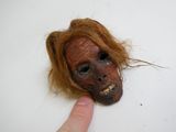une personne montrant du doigt un masque à l'aspect effrayant posé sur une table