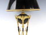 une image représentant une lampe noire et dorée, surmontée d'un abat-jour noir