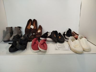 Plusieurs paires de chaussures sont alignées sur une étagère devant un mur blanc