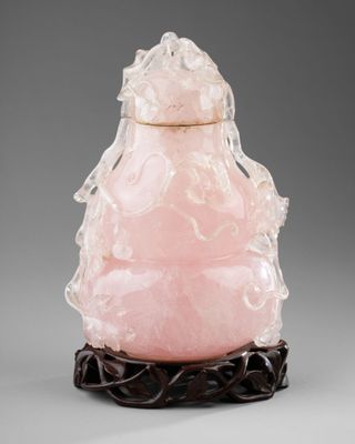 une tabatière en jade rose ornée de figures sculptées, posée sur un socle
