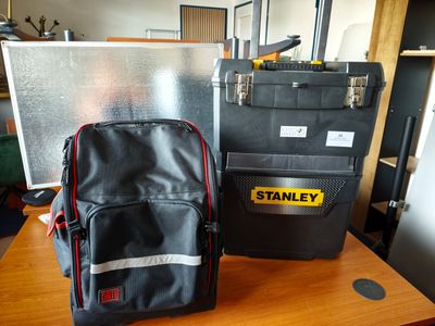 un sac à dos noir et une trousse à outils noire et jaune posés sur une table