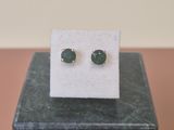 a pair of green stone stud earrings sitting on top of a marble block