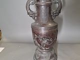 a silver vase sitting on a table next to a gold vase