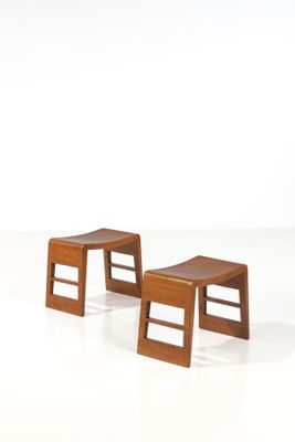 deux petits tabourets en bois placés l'un à côté de l'autre sur une surface blanche