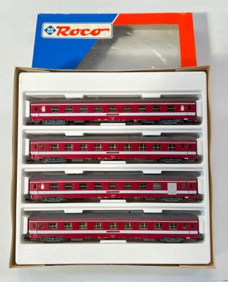 six wagons rouges et blancs se trouvent dans une boîte posée sur une surface blanche