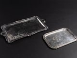 two silver trays on a black table with a black background