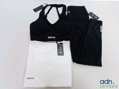 un haut de sport et un legging noir et blanc posés sur une table blanche