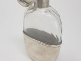 a small glass jar with a silver lid on a white surface