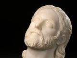 a white marble bust of a man with long hair and beard