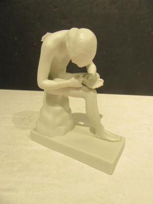 une statue blanche représentant un homme assis sur un banc