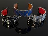 three different colored bracelets sitting on top of a black surface