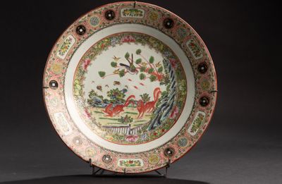 une assiette décorée d'un oiseau, posée sur un socle