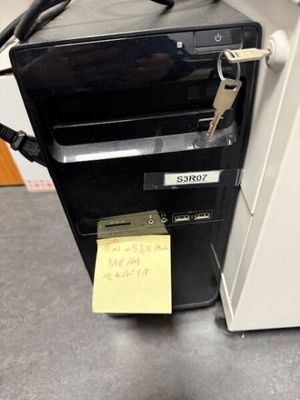 un ordinateur posé sur un bureau, avec un mot accroché dessus