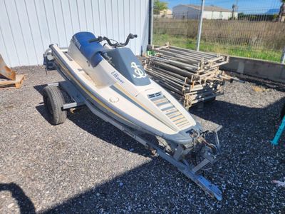a boat that is sitting on a trailer in the gravel