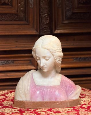 une statue représentant une femme assise sur une nappe rouge et dorée