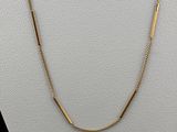 a gold plated necklace with a curved bar on a white mannequin