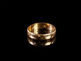 gros plan d'une bague en or sur une surface noire