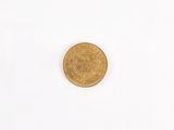 a gold coin on a white surface with a white background