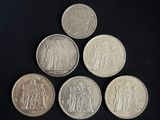 six different british coins are arranged on a black surface