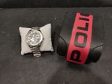 a watch sitting next to a pillow on a black surface