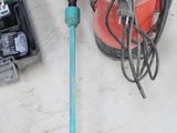 une perceuse et d'autres outils posés par terre à côté d'un tas d'autres outils