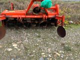 a red tractor with a plow attached to it on the side of the road