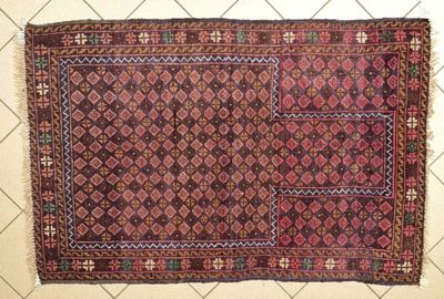 a close up of a rug on a tiled floor with a wall in the background