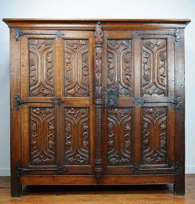 an antique oak cupboard with carved panels and metal handles