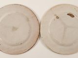 two white plates with brown spots on them sitting on a white surface