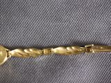 a close up of a gold bracelet with a coin on it
