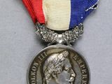 une photo représentant une médaille entourée d'un ruban, posée sur une table