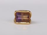 a close up of a gold ring with a purple stone