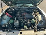 un moteur de voiture dont le capot est ouvert, garé dans la rue