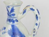 a blue and white vase with a handle on a table