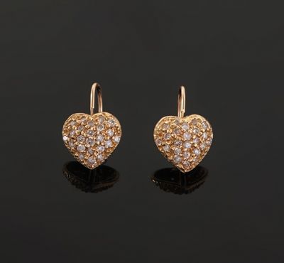 a pair of gold and diamond heart earrings on a black surface
