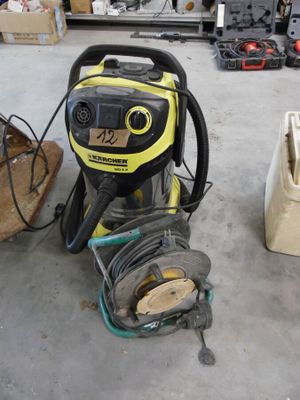 un aspirateur jaune et noir dans un garage, à côté d'autres outils